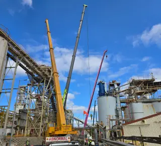 Picture of three cranes moving heavy machinery on a job site