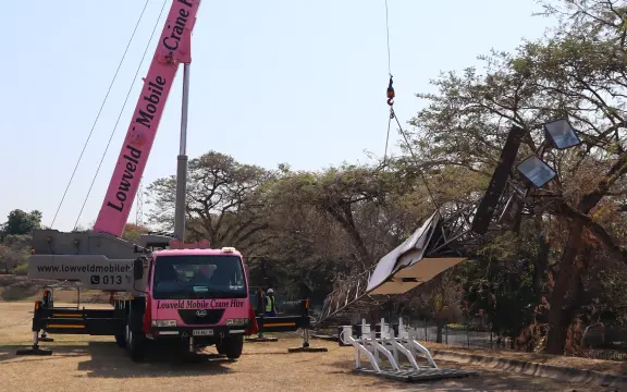A picture of the Pink Lady crane lifting a stadium light at Lowveld High School